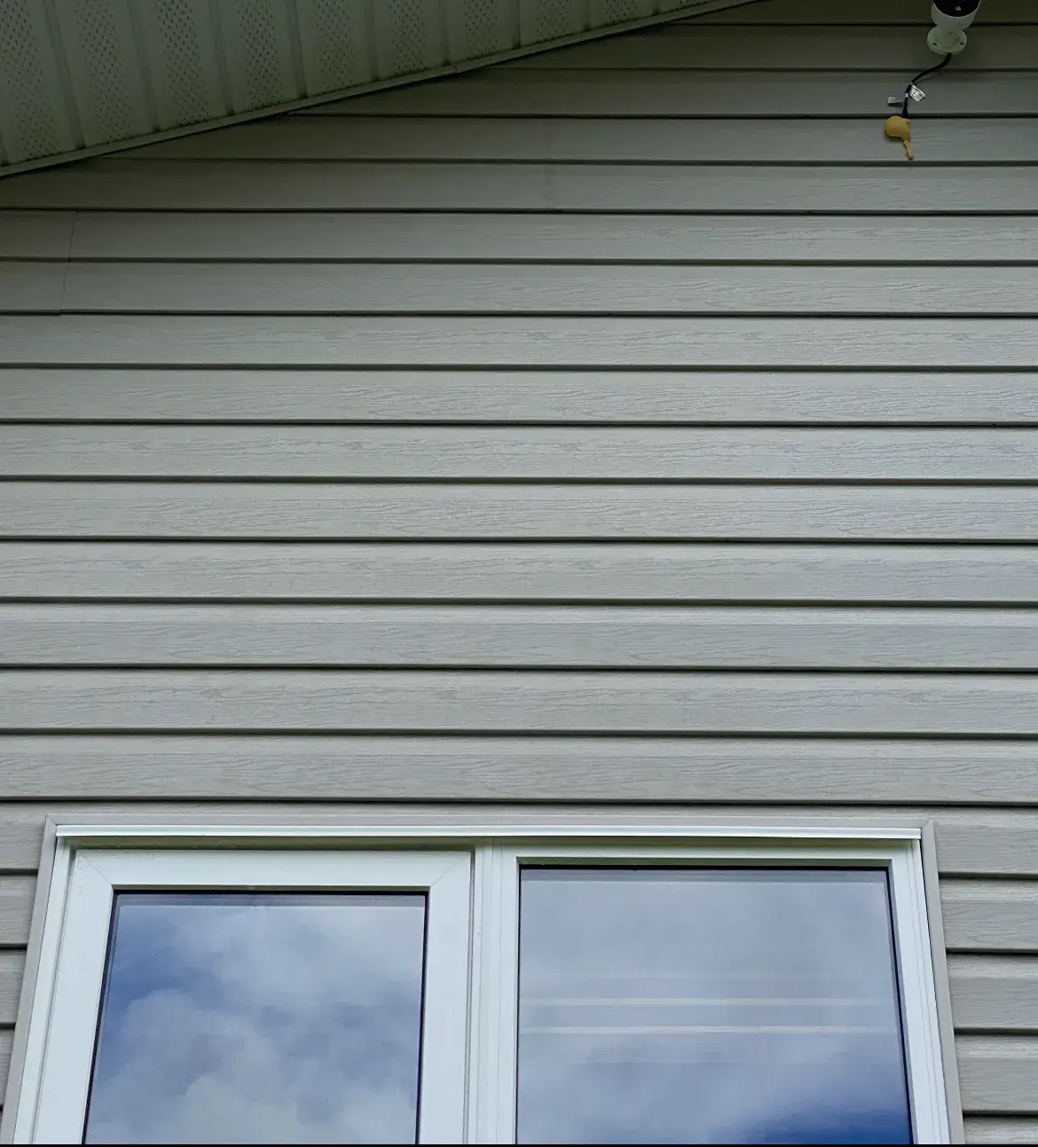 Sage-green vinyl siding and soffit after soft washing, with the horizontal streaking removed